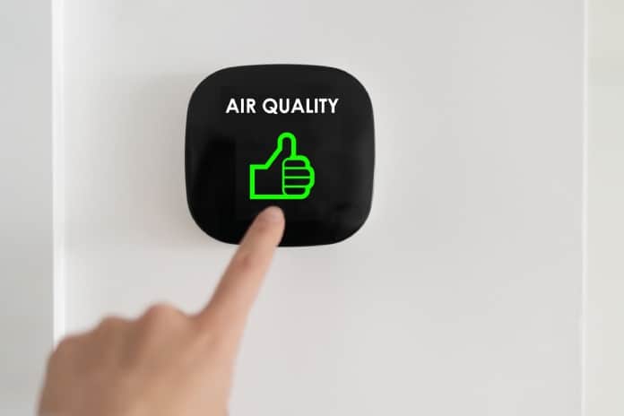 An smart technology indoor touchscreen mounted to the wall, showing a thumbs up icon for good air quality.