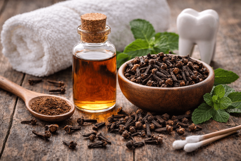 Clove oil bottle with dried cloves and cotton swabs on wooden table for natural toothache relief and safe DIY dental use